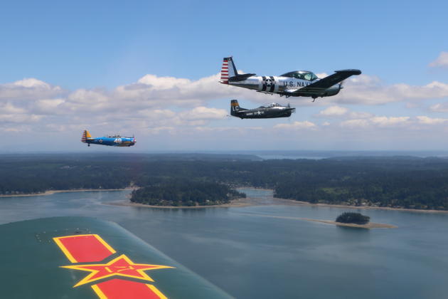 Roger Collins in his T-28, Smokey Johnson and Bob Meyer in Roger's T-6, plus Dave Desmon and Dan Shoemaker in the Navion, cruising over the Puget Sound en route to the Memorial Day flyby. Photo by Walt Cannon.