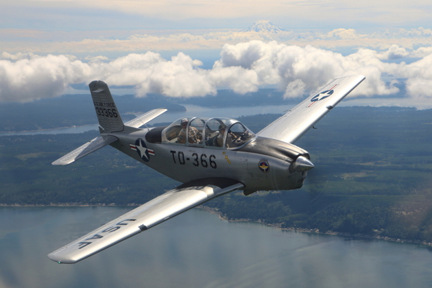 Alyssa 'Smiley' McColly banking with Jim Ostrich's T-34 over Puget Sound waterways, with Mt. Rainier in the distance.