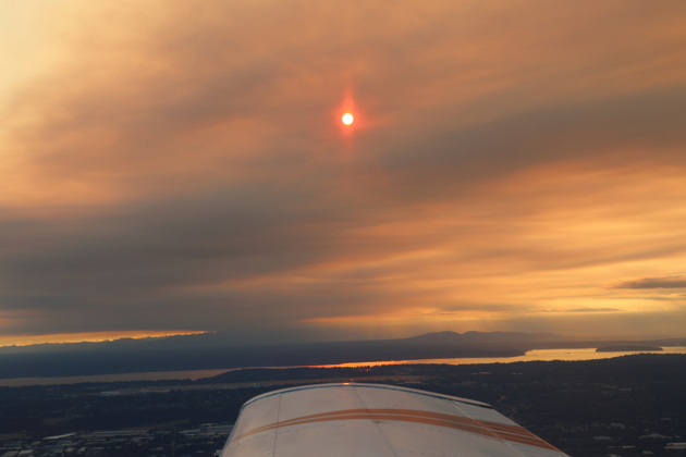 Smoke from the Bear Gulch fire creating an eerie sunset view over the Olympic Mountains while returning from August Kachina flying. My photo.