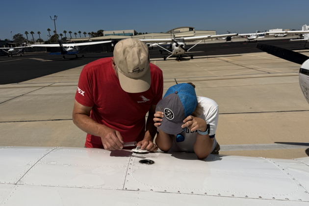 Checking fuel levels during pre-flight with Nathaniel at Long Beach, CA. Photo by David Kasprzyk.
